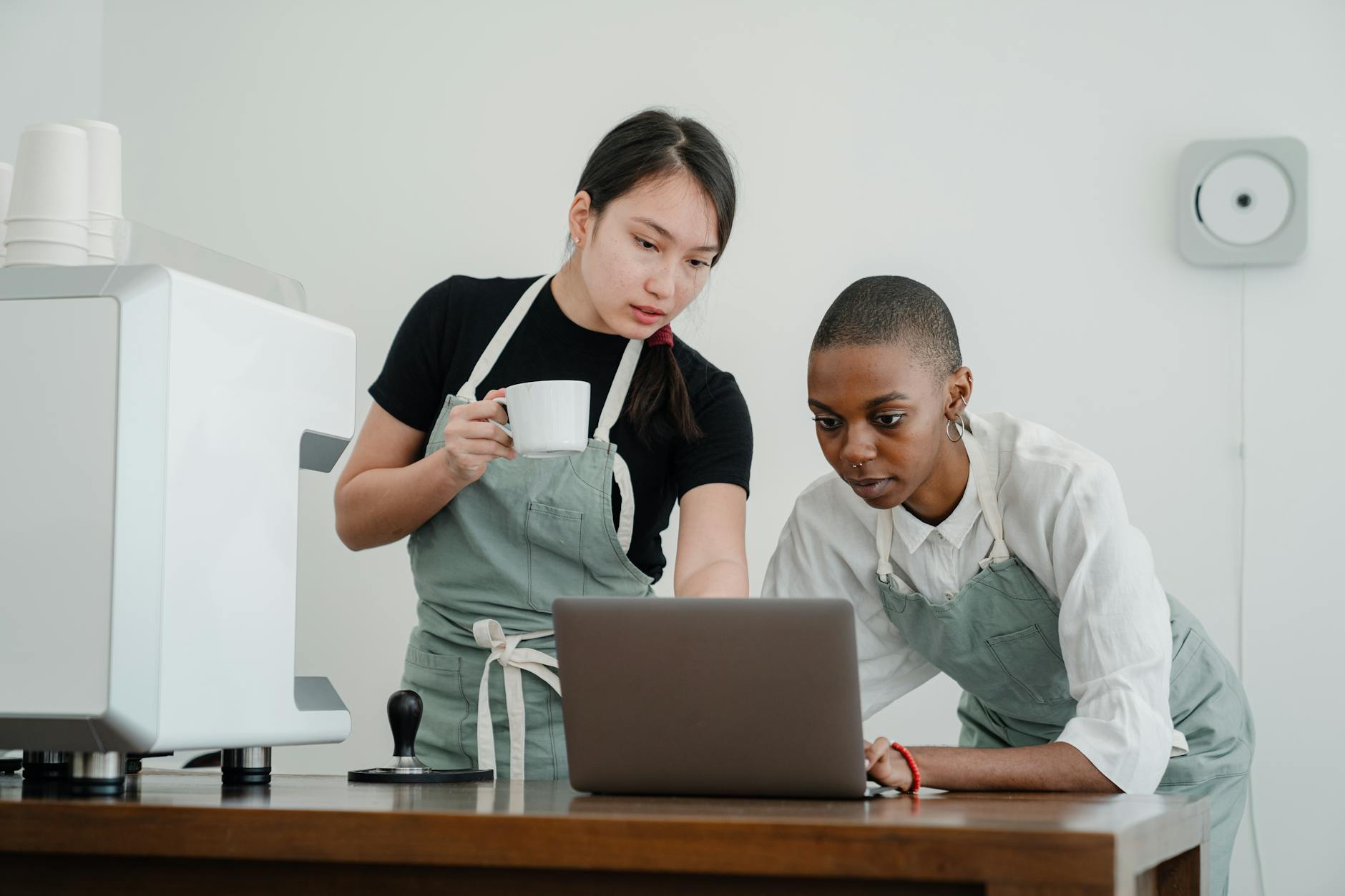 young diverse coworkers at coffee shop using laptop together
