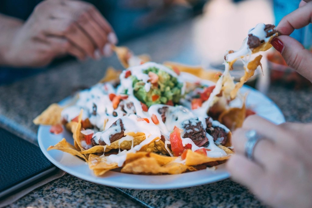 People sharing plate Mexican nachos