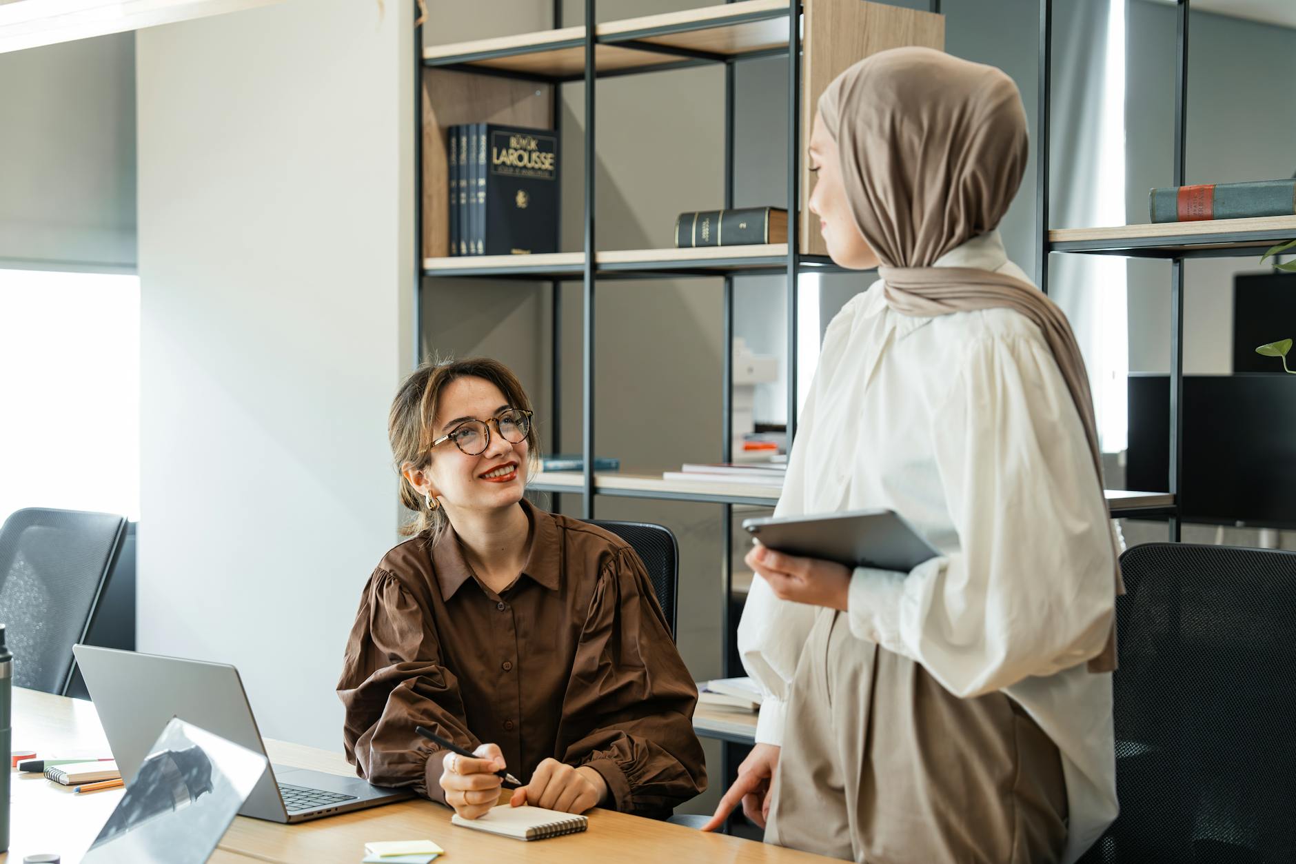 two women in an office interior with shelves