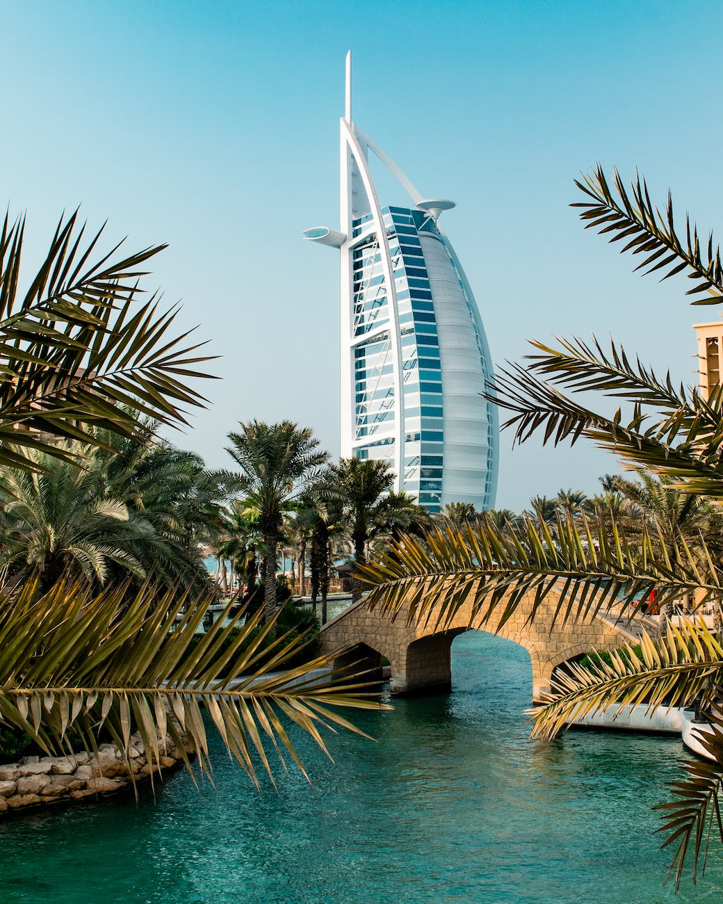 building of the the burj al arab hotel behind palm trees and a bridge dubai united arab emirates